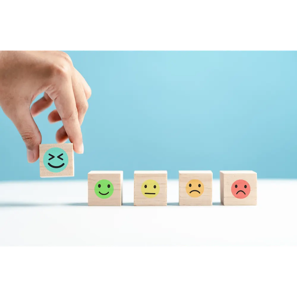 Hands placing a smiling face block above a row of mood faces